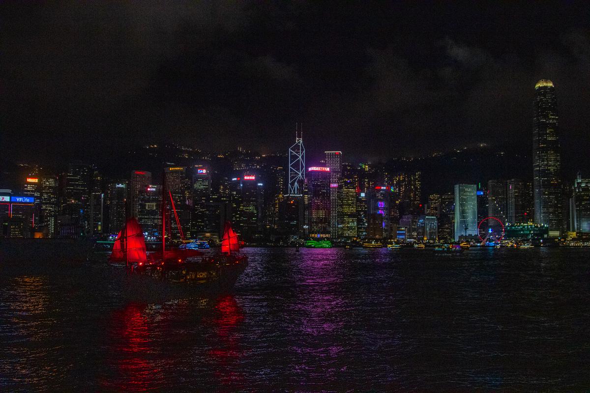 red-sailed junk boat crossing hong kong harbor at night