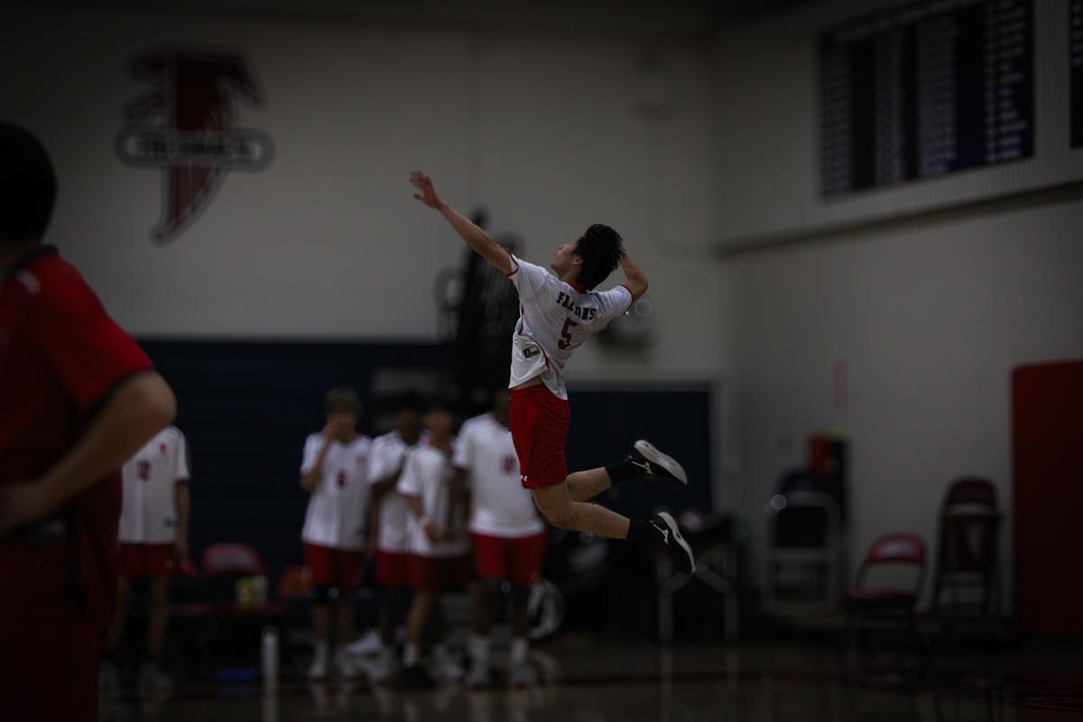 Volleyball player mid-air jump serve in a gymnasium